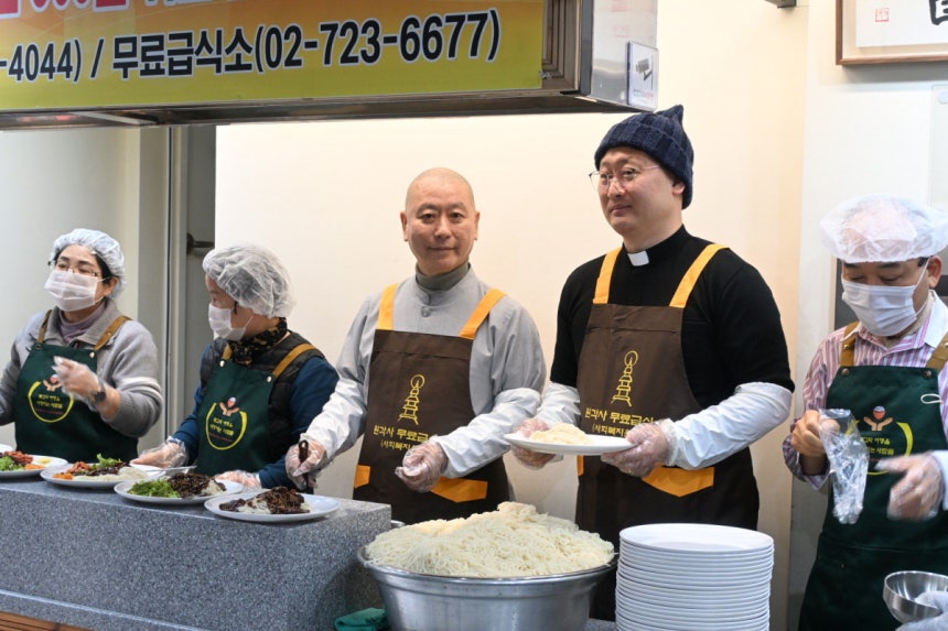 28일 서울 종로구 원각사에서 원경 스님(왼쪽에서 세번째)과 이문수 신부(왼쪽에서 네번째)가 노인·노숙인 무료 급식에서 배식하고 있다.강한들 기자