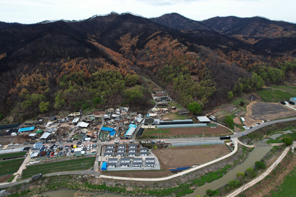 2025년 4월23일 오후 경북 안동시 일직면 명진리에서 산불로 집을 잃은 주민을 위한 이동주택(아래쪽) 입주식이 열리고 있다.산 아래쪽에 불탄 집들이 보인다.무인기를 띄워 찍었다.