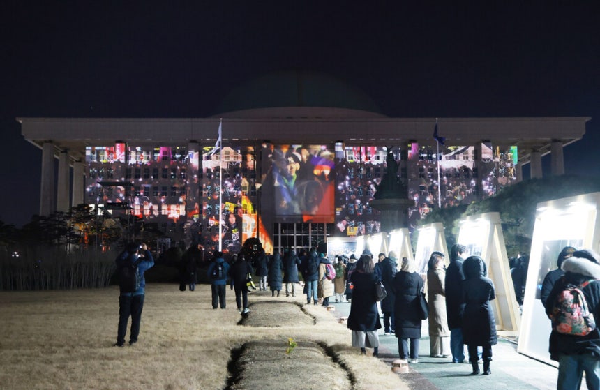 2025년 12월3일 서울 여의도 국회의사당에서 열린‘비상계엄 해제 1주년 기억행사\'에서 당시 상황을 되새기는 미디어파사드가 본관 외벽에 투영되고 있다.연합뉴스