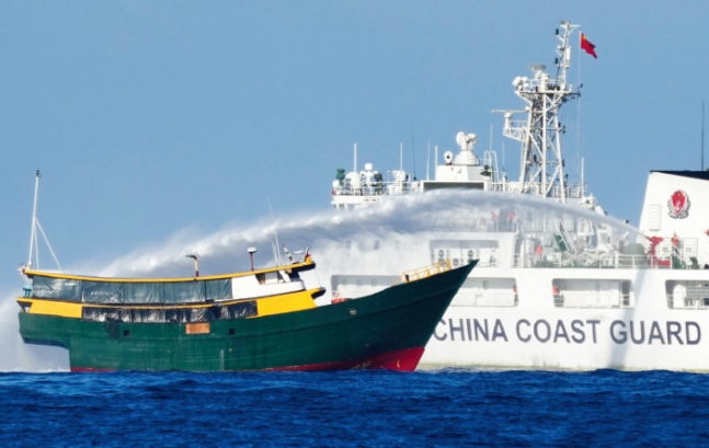 A People's Republic of China Coast Guard vessel, right, fires a water cannon at a Republic of the Philippines supply ship in waters near the Spratly Islands in the South China Sea (Spratly Islands with People's Republic of China and Republic of the Philippines Kalayan Islands) on March 5 (local time). [Newsis]