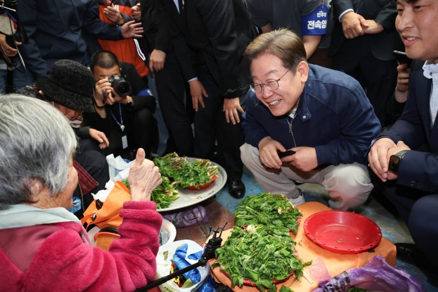 더불어민주당 이재명 대선 후보가 '골목골목 경청투어' 접경지역 방문 이틀째인 2일 강원도 인제군 원통전통시장에서 엄나무순을 사며 어르신과 대화하고 있다.  사진=연합뉴스