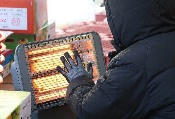 경기 수원시 팔달구 영동시장에서 상인들이 전기난로에 몸을 녹이고 있다. photo 뉴스1