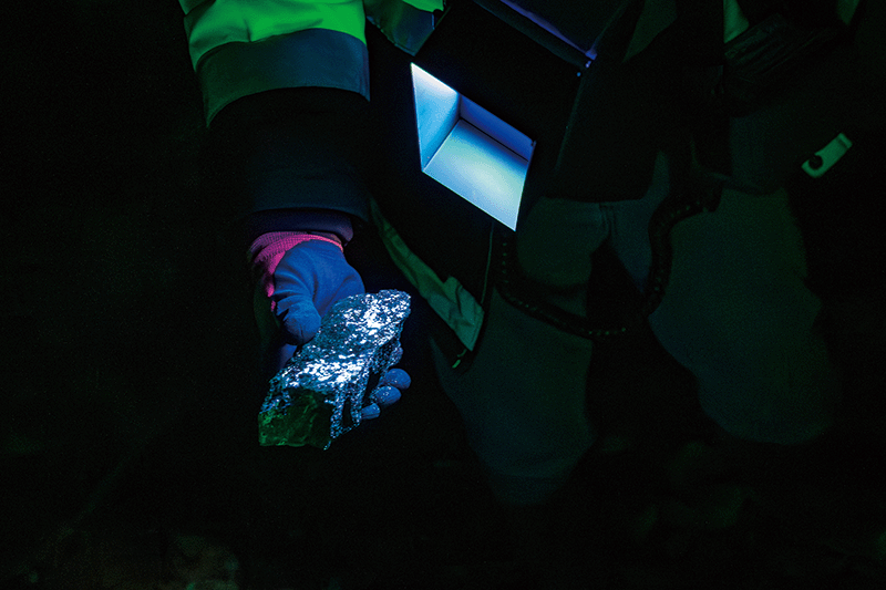 텅스텐 원석에 자외선 램프를 비추자 푸른색으로 빛나고 있다.