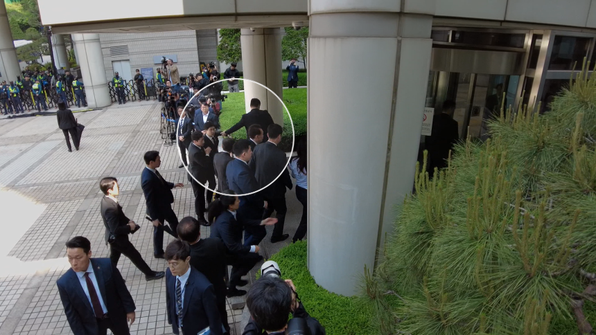 내란 우두머리 혐의로 재판을 받고 있는 윤석열 전 대통령이 처음으로 법원에 공개 출석하는 과정에서, 경호원들은 윤 전 대통령에게 질문하려는 KBS 기자의 두 팔과 허리 등을 강하게 잡아 끌며 취재를 방해하고 있다. 