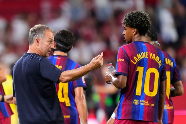 Barcelona's head coach Hansi Flick, left, talks with Barcelona's Lamine Yamal, second from right, and Raphinha, right covered, during the Spanish La Liga soccer match between Sevilla and Barcelona in Seville, Spain, Saturday, Sept. 19, 2026. (AP Photo/Jose Breton)
