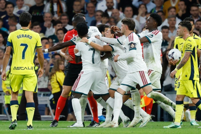 Real Madrid's Brazilian forward #07 Vinicius Junior (C) is restrained by teammates as he argues with referee Isidro Escuderos after receiving a red card during the Spanish league football match between Real Madrid CF and Villarreal CF at the Santiago Bernabeu Stadium in Madrid on October 10, 2026. (