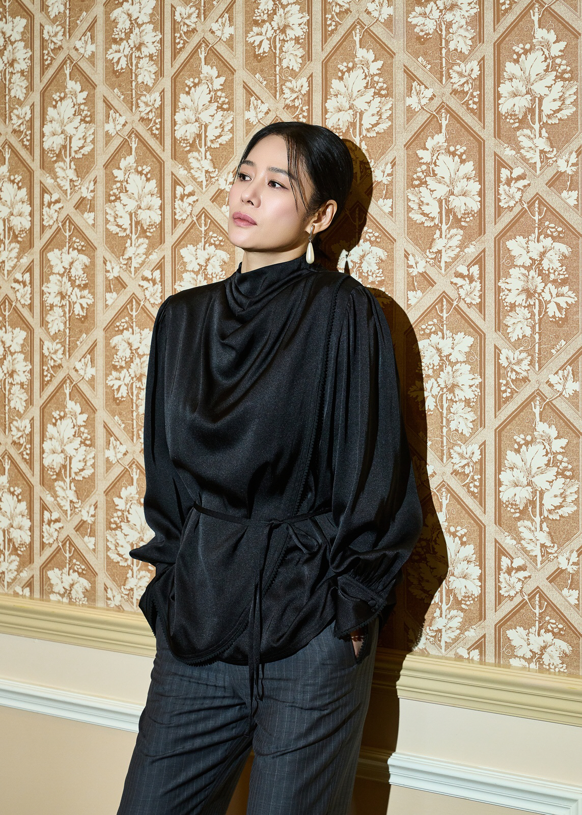 黒い衣装で壁を背に立つキム・ヒョンジュ