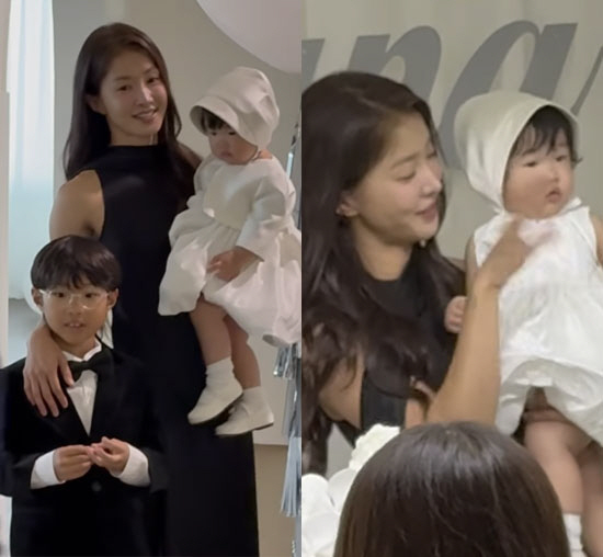 黒いドレス姿のイ・シヨンが、白い衣装の娘を抱き、タキシード姿の息子と並ぶ誕生会の写真