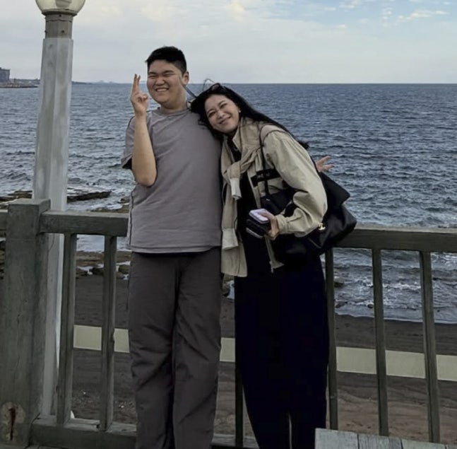海辺の柵の前で肩を寄せて並ぶオ・ユナと息子のミンさん