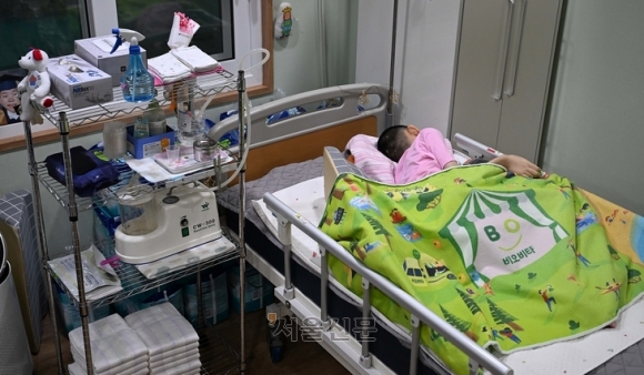 시각장애와 분열뇌증을 앓고 있는 생명이가 22일 서울 금천구 주사랑공동체교회 장애인단기보호센터 침대에서 휴식을 취하고 있다. 지난 2011년 베이비박스에 놓인 생명이는 13년째 교회와 센터 관계자들의 보호를 받고 있