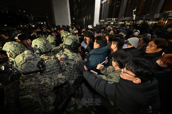 윤석열 전 대통령이 계엄령을 선포한 지난해 12월 3일 서울 여의도 국회에 진입한 군인들을 시민과 국회 보좌진들이 막아서고 있다.도준석 전문기자