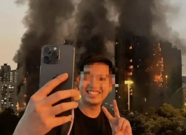 홍콩의 유튜버 천모(26)씨가 지난달 27일 화재가 발생한 아파트 단지 ‘웡 푹 코트’를 찾아 화염에 휩싸인 아파트를 배경으로 ‘셀카’를 찍고 있다. 자료 : 스레드
