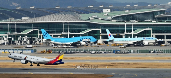 22일 인천 중구 인천국제공항 제2터미널에 주기된 대한항공 여객기와 활주로에서 이동하는 아시아나항공 여객기 모습.공정거래위원회는 이날 대한항공이 제출한 아시아나항공 마일리지 수정 통합안을 다시 반려했다.대한항공은