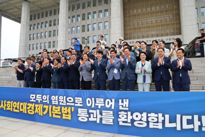 더불어민주당 사회연대경제위원장인 복기왕(아랫줄 오른쪽에서 여섯 번째) 의원을 비롯한 여권 의원들이 지난 20일 국회에서 사회연대경제기본법이 통과하자 국회 본관 앞에서 이를 기념하며 박수를 치고 있다. 복기왕 의원실 