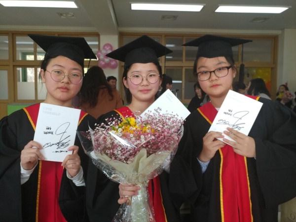 BTS Jimin gives out signed music CDs to graduating students from his elementary school.