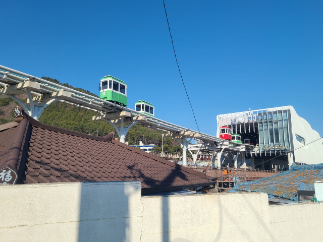 블루라인파크 청사포정거장에서 뻗어 나온 고가 궤도 위로 장난감 같은 빨강, 파랑, 노랑, 초록 스카이캡슐이 오가고 있다.