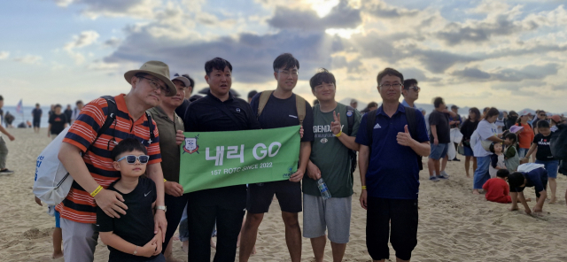 모임 이름이 적힌 깃발을 펼쳐 들고 기념 사진을 찍고 있는 국립 부경대 ROTC 동문회 내리 GO 회원들. 이들은 정기 모임 일정을 앞당겨 다대포 세븐비치 어싱 챌린지에 참가했다. 김희돈 기자