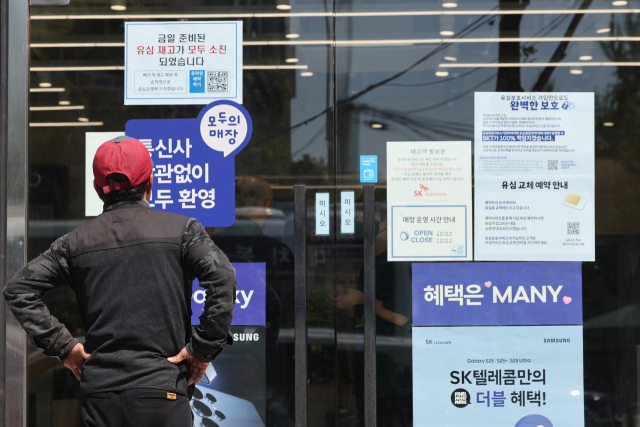 SK텔레콤이 가입자 유심(USIM) 정보 유출 사태로 5일부터 신규 가입자 모집을 중단한다고 밝힌 지난 2일 서울 시내의 한 SK텔레콤 대리점 앞에서 한 소비자가 유심 재고 소진 및 유심보호서비스 관련 안내문을 살펴