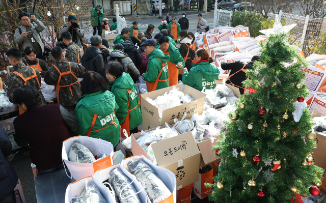 크리스마스를 하루 앞둔 24일 서울 동대문구 밥퍼나눔운동본부에서 열린 거리 성탄 예배에서 자원봉사자들이 참가자들에게 음식과 생필품 등을 전달하고 있다.연합뉴스