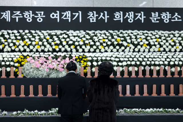 12·29 제주항공 여객기 참사 1주기를 하루 앞둔 28일 전남 무안국제공항 1층 합동분향소에서 추모객들이 헌화하고 있다.연합뉴스