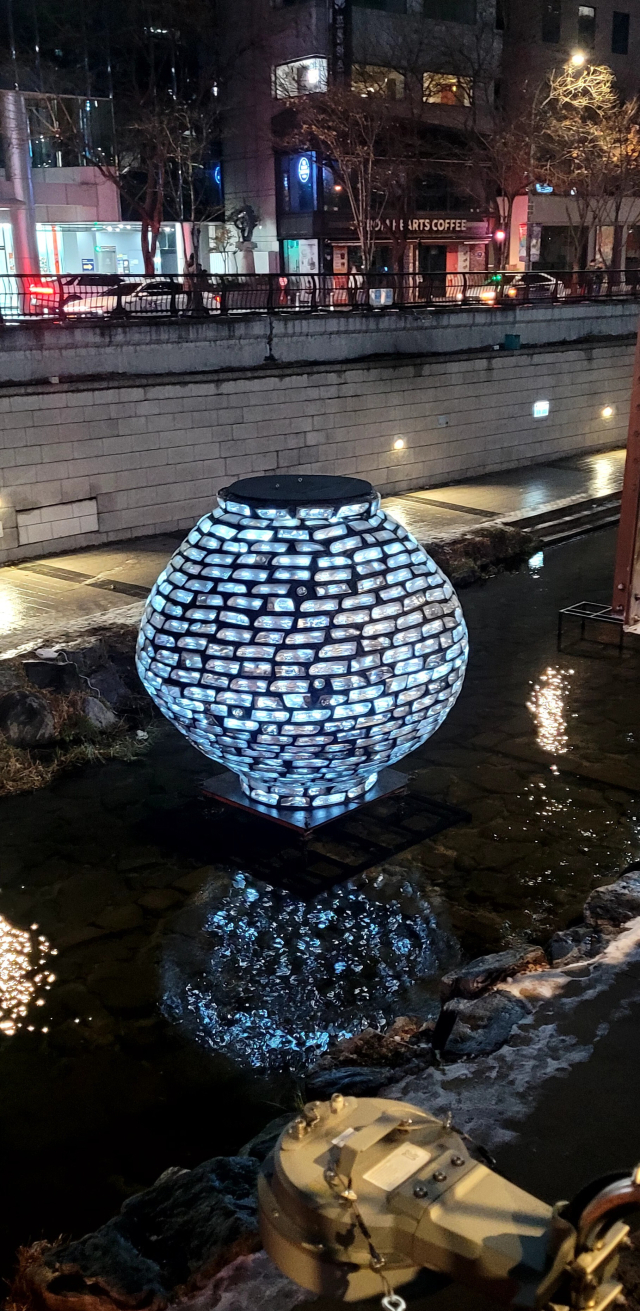 서울 광교 근방 청계천 물 위에 띄운 폐헤드라이트로 만든 달항아리 모양의 ‘환월'(還月) 설치 모습. 1월 15일께부터는 부산 해운대구 달맞이공원에 설치될 예정이다. 작가 제공