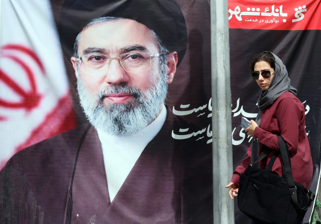 19일(현지 시간) 이란 테헤란의 한 거리에서 시민이 이란 최고 지도자 아야톨라 하메네이의 사진 앞을 지나가고 있다. 호르무즈해협이 봉쇄된 가운데 미국과 이란의 종전 협상은 결론을 내지 못하고 서로 다른 입장차만 확