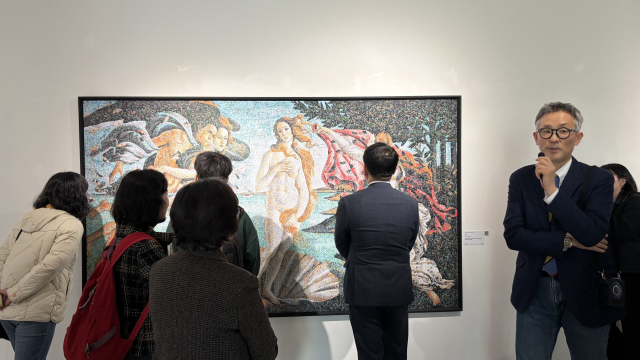 지난달 금정문화회관 금샘미술관에서 개막한 ‘지구 앞에 서다_위태로운 경계에서’ 선보인 크리스 조던의 '비너스'를 자세히 살펴보는 관람객들. 보티첼리의 명화 ‘비너스의 탄생’을 차용한 이 작품은 24만 개의 비닐봉지로