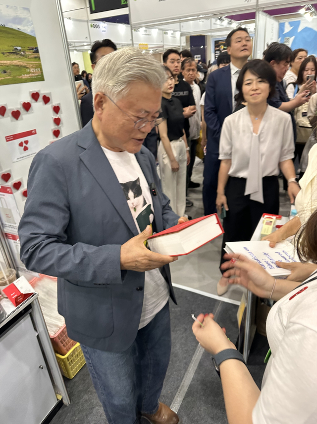 최근 막을 내린 '2026 서울국제도서전'에서 부산출판문화산업협회 연합 부스를 찾은 문재인 전 대통령이 정철교 작가의 새 책 <붉은 선으로 가둔 하루들, 나의 2021년>을 뮤트스튜디오 이보리 대표로부터 