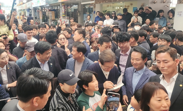 더불어민주당 이재명 대선 후보가 4일 영월 서부시장을 찾아 한 시민의 책에 사인을 하고 있다.