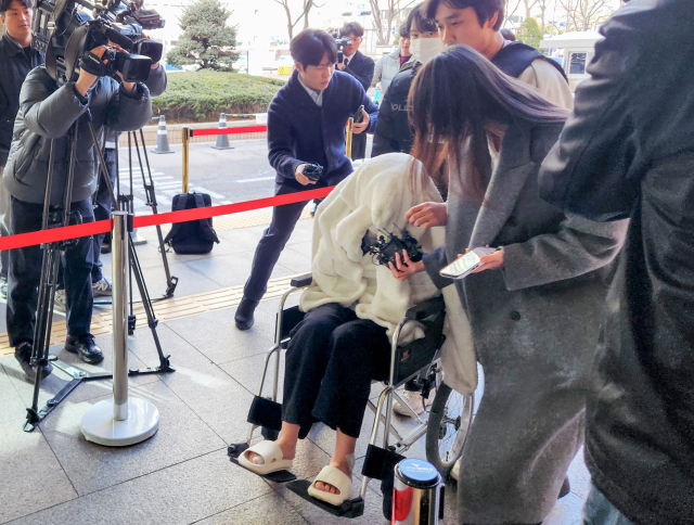 약에 취한 상태로 외제 SUV 차량을 몰고 반포대교를 달리다 한강 둔치로 추락한 운전자 A씨가 27일 서울 마포구 서부지방법원에서 열린 구속 전 피의자 심문(영장실질심사)에 옷으로 얼굴을 가리고 휠체어를 탄 채 출석