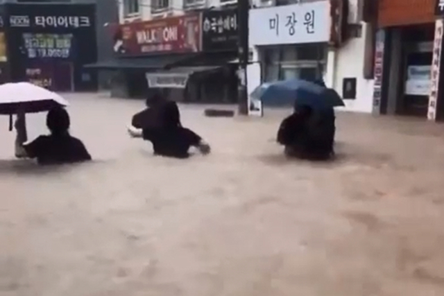 광주 전역에 폭우가 쏟아진 17일 오후 광주 북구 용봉동 거리에서 시민과 학생이 가슴 높이까지 차오른 흙탕물을 헤치며 귀가하고 있다. 연합뉴스