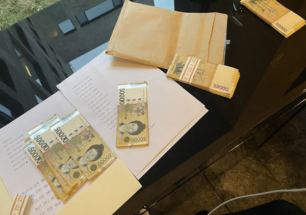 2021년 문재인 전 대통령의 부인 김정숙 여사의 맞춤 의상 옷값으로 지불됐다는 현찰과 관봉권의 모습. A4 용지에는 김 여사가 구매해 간 것으로 추정되는 258만원 상당의 코트, 178만원 상당 재킷, 88만원 상