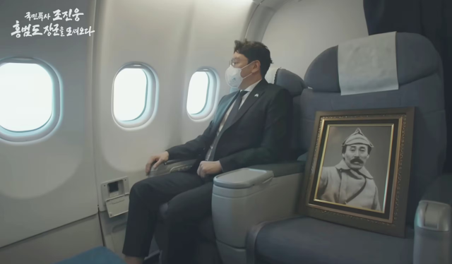 문재인 정부 시절이던 2021년 8월 국민 특사 자격으로 카자흐스탄에서 홍범도 장군 유해를 가져오고 있는 배우 조진웅.옆자리에 홍범도 장군 영정이 놓여있다.KBS