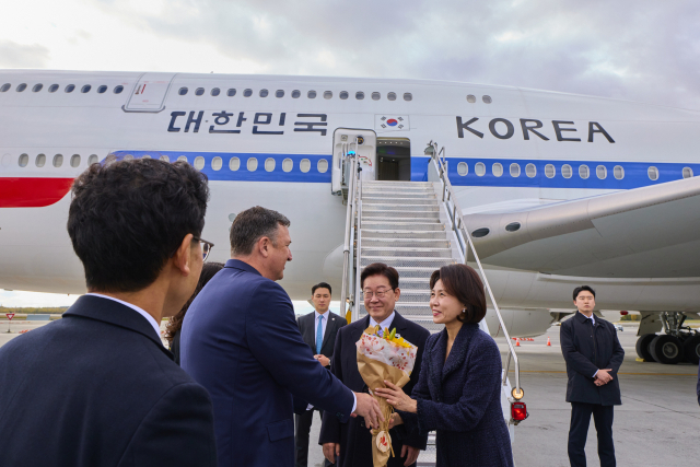 미국·멕시코 순방을 마친 이재명 대통령과 김혜경 여사가 26일(현지시간) 귀국길 경유지인 미국 알래스카주 앵커리지 테드 스티븐스 국제공항에서 영접 인사로부터 꽃다발을 받고 있다. 연합뉴스