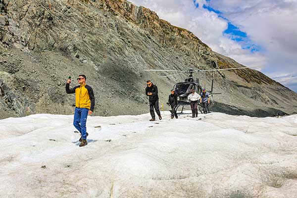 빙하 위에 착륙한 헬리콥터에서 내리는 탐승객들.