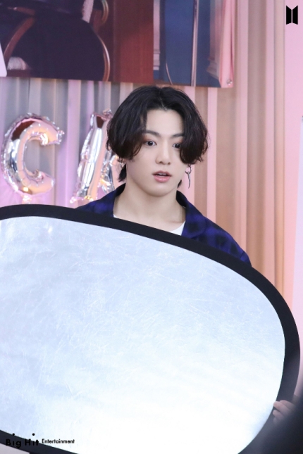 Photo of BTS Jungkook showing his perm hairstyle with a bangs.
