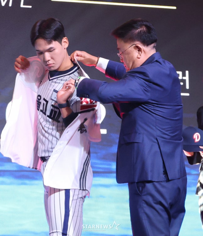 서울고 김지우(왼쪽)가 9월 21일 '2027 KBO 신인 드래프트'에서 전체 2순위로 두산 베어스에 지명된 후 김태룡 단장으로부터 유니폼을 건네 받고 입어 보고 있다. /사진=김진경 대기자