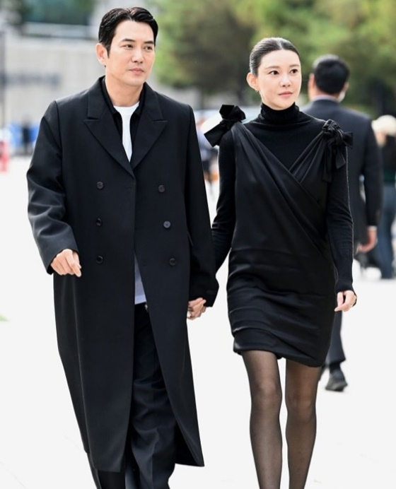 デザイナーブランドのイベントに出席し、黒いロングコート姿で妻チャ・イェリョンと手をつないで歩くチュ・サンウク