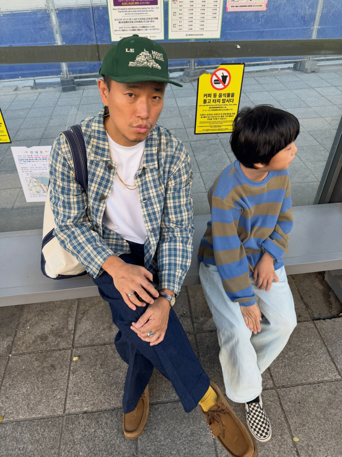 屋外のベンチに並んで座るカン・ゲリと息子のハオ