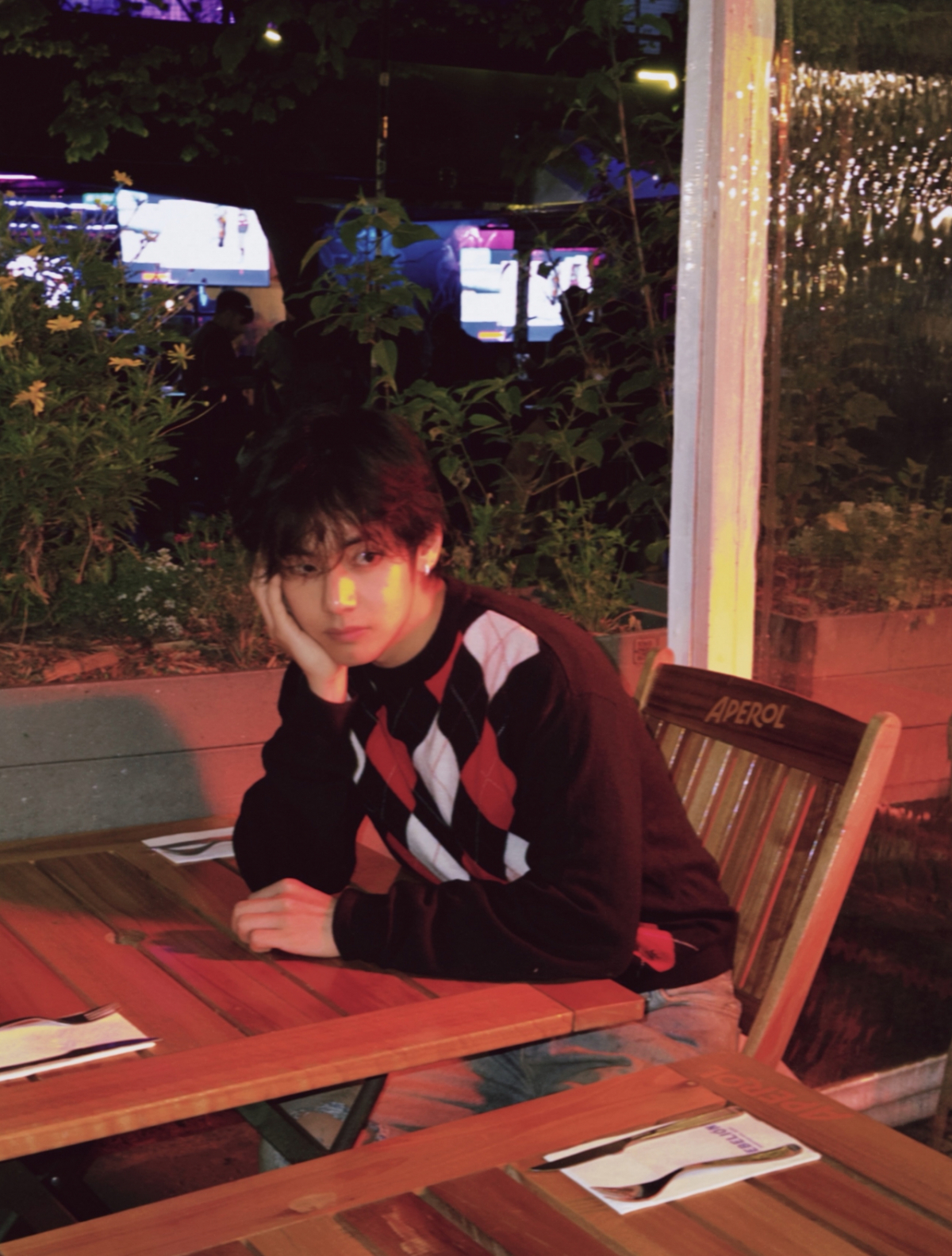 アルゼンチンの夜、テーブルに頬杖をついてカメラを見るBTSのV