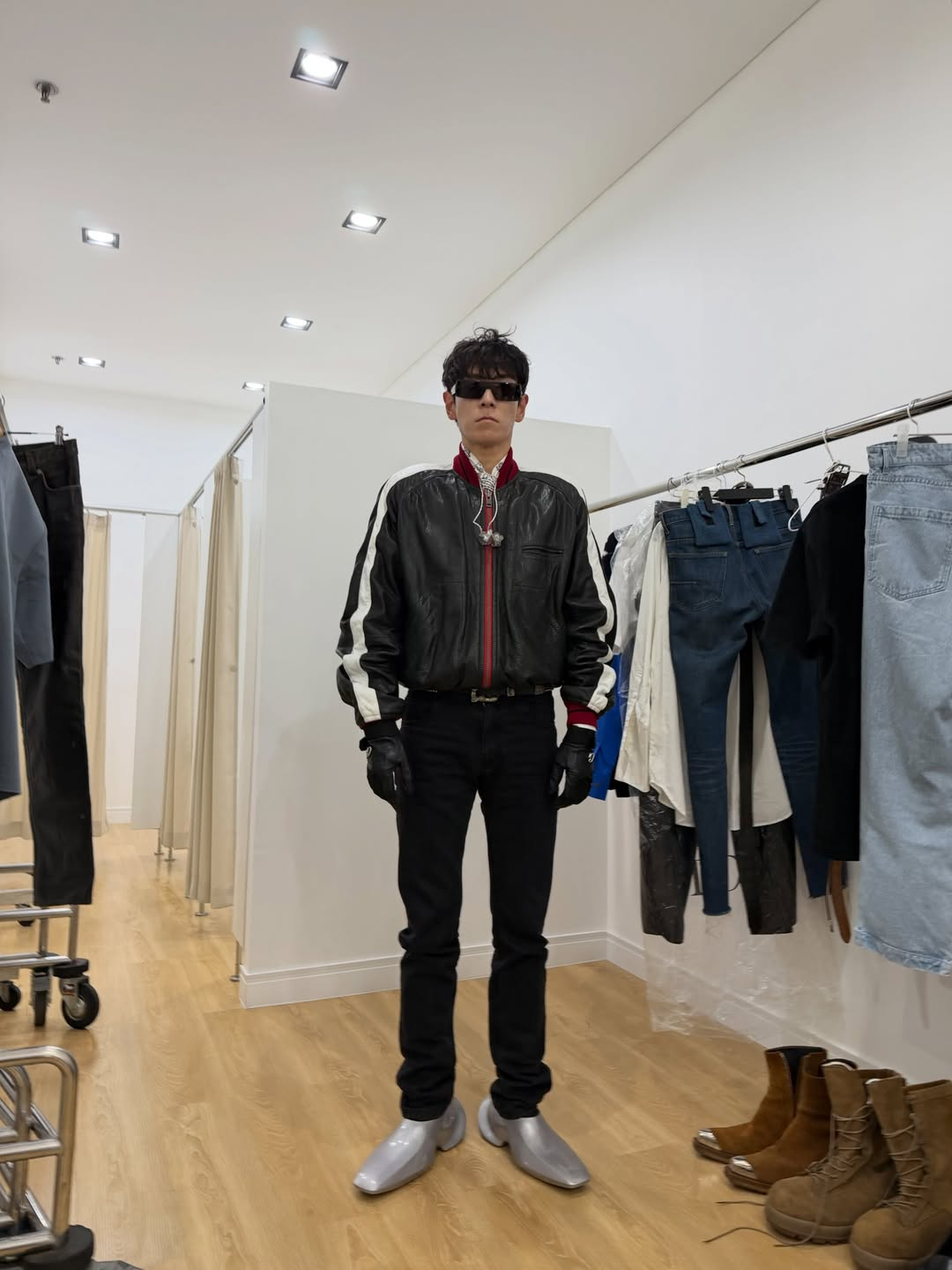 試着室で黒いレザージャケットと黒いパンツ、銀色の靴を合わせたT.O.P。