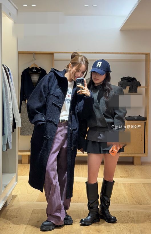 ショップでコートを試着し、チョ・ヒョナと鏡越しに写真を撮るヒョミン