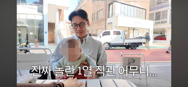外出先で生後6カ月の息子を抱くオ・サンジン。息子の顔にはぼかしが入っている