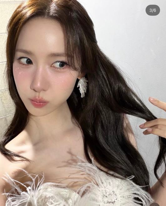羽根飾りのトップスと青みのあるメイクでポーズを取るユナ