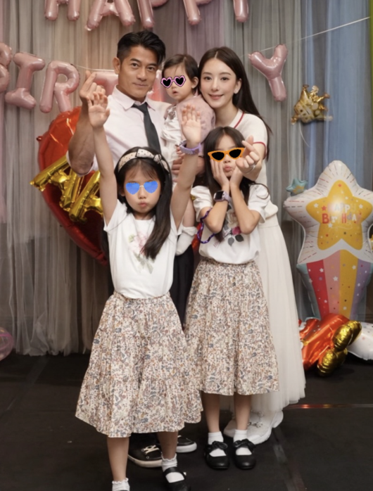 誕生日の飾り付けを背景に、妻ファン・ユエンと3人の娘と並ぶアーロン・クォック