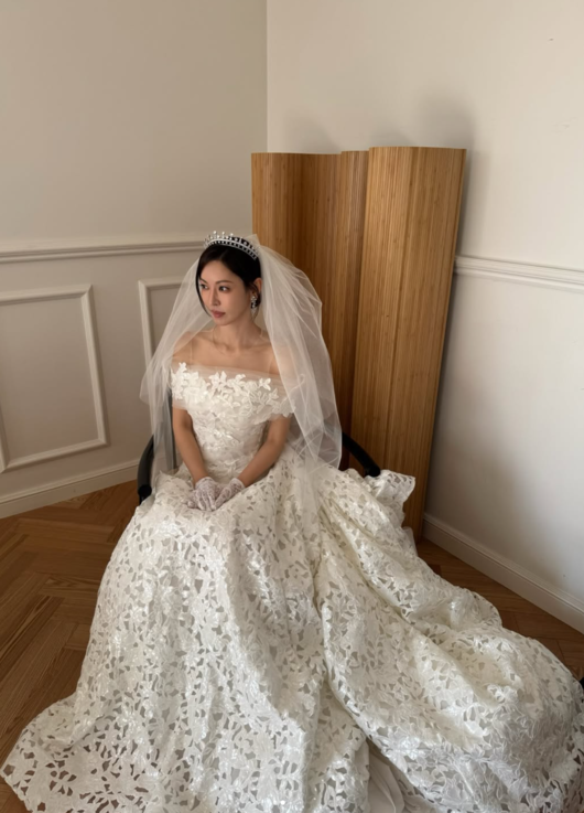 白い花柄のウェディングドレスとベール、ティアラを身に着け、椅子に座るキム・ソヨン
