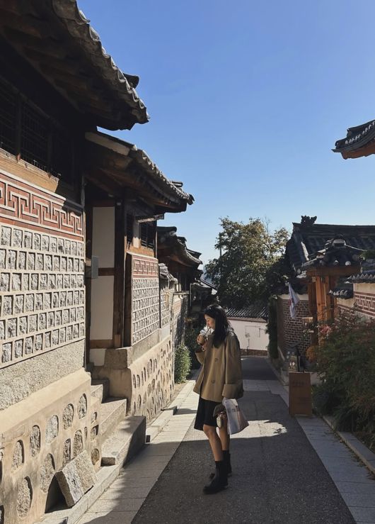 北村の路地で、ブラウンのコートと黒いスカート、ブーツを合わせたソ・スヨン