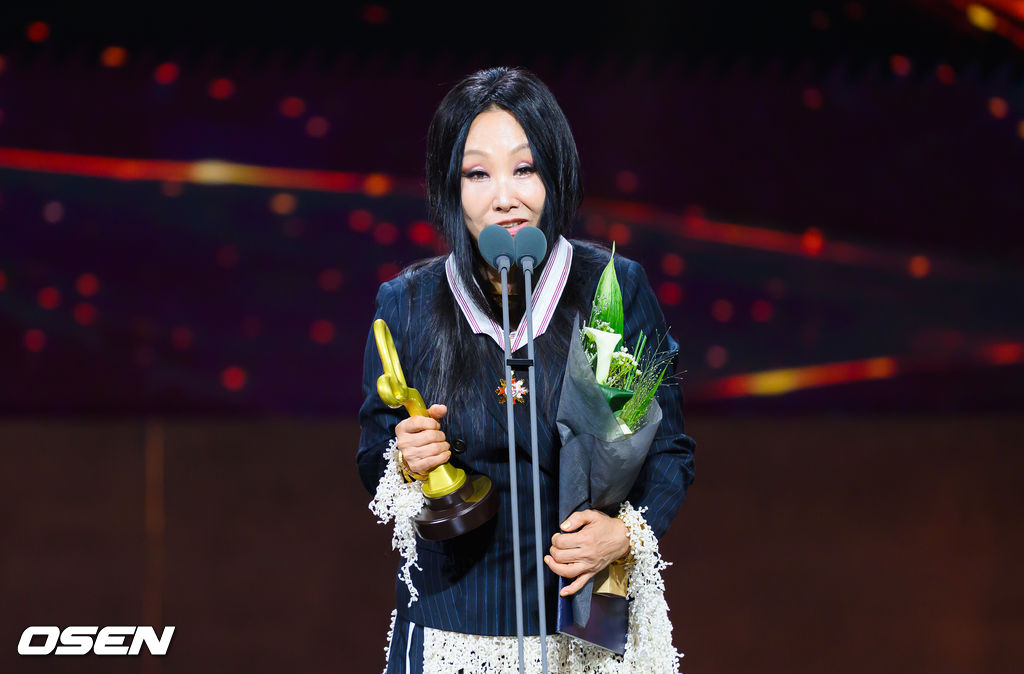 ボガン文化勲章を受章したハン・ヨンエが、花束とトロフィーを手にマイクの前で受賞所感を述べる