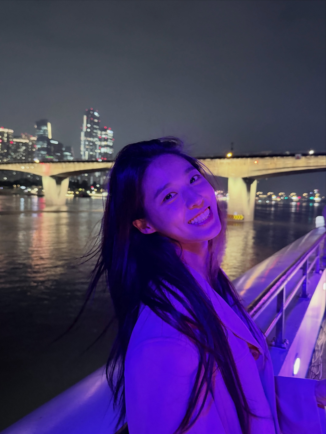 夜景と橋を背景に、白い服を着て笑顔を見せるソルヒョン。