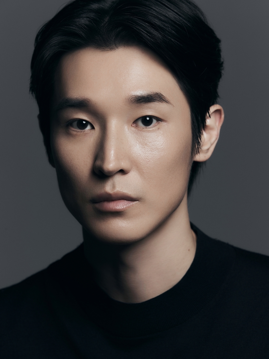 黒い服を着て正面を見つめる俳優ウ・ジヒョンのポートレート